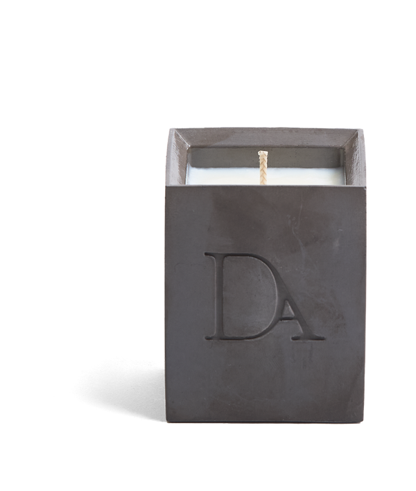 4oz Devetu artisanal candle in Apollo, crafted in a gunmetal black concrete square vessel. The candle is uncovered, displaying the richly textured wax surface, with the 'DA' Devetu Aroma logo embossed on the front.