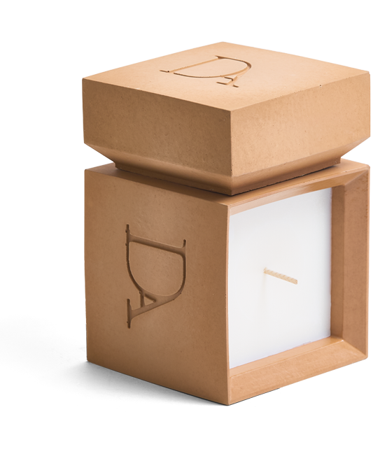 9oz Devetu artisanal candle in Embrace, encased in warm cashew colored concrete square vessel with a lid. The lid, featuring the embossed 'DA' Devetu Aroma logo, adds a sleek finish to the candle's modern aesthetic.