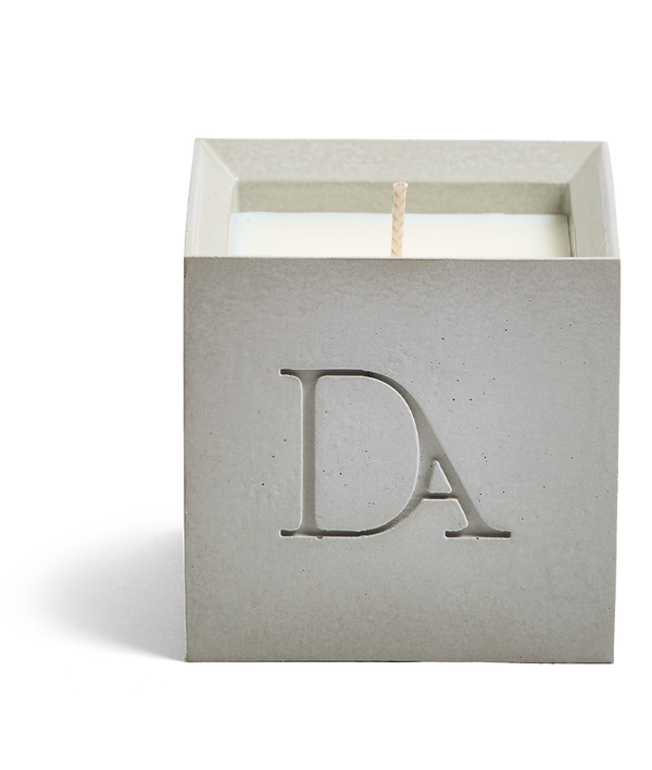 9oz Devetu artisanal concrete square candle named Skin, uncovered, showcasing the richly textured wax surface, in natural concrete with āDAā Devetu Aroma logo embossed on the front.