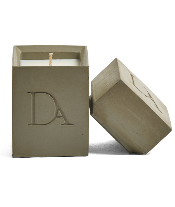 4oz Devetu artisanal candle in Wild Nomad, encased in deep olive green concrete square vessel with a lid. The lid, featuring the embossed 'DA' Devetu Aroma logo, adds a sleek finish to the candle's modern aesthetic.