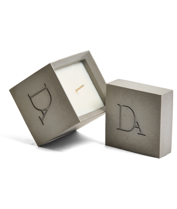 9oz Devetu artisanal candle in Odyssey, encased in ash grey concrete square vessel with a lid. The lid, featuring the embossed 'DA' Devetu Aroma logo, adds a sleek finish to the candle's modern aesthetic.
