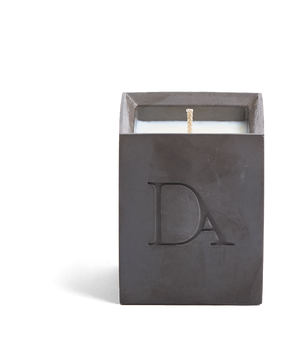 4oz Devetu artisanal candle in Apollo, crafted in a gunmetal black concrete square vessel. The candle is uncovered, displaying the richly textured wax surface, with the 'DA' Devetu Aroma logo embossed on the front.