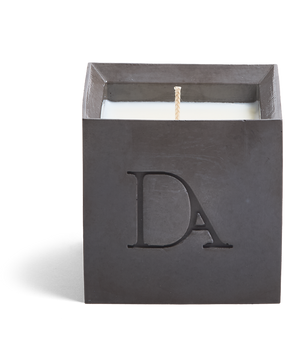 9oz Devetu artisanal candle in Apollo, crafted in a gunmetal black concrete square vessel. The candle is uncovered, displaying the richly textured wax surface, with the 'DA' Devetu Aroma logo embossed on the front.