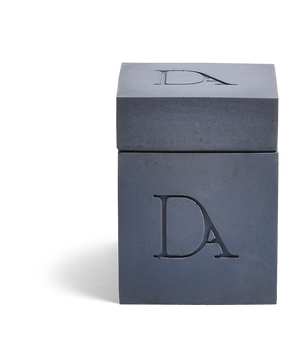 9oz Devetu artisanal candle in Elysian, encased in deep navy concrete square vessel with a lid. The lid, featuring the embossed 'DA' Devetu Aroma logo, adds a sleek finish to the candle's modern aesthetic.