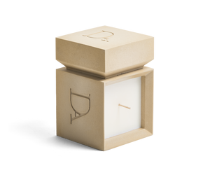 9oz Devetu artisanal candle in Gravity, encased in soft taupe concrete square vessel with a lid. The lid, featuring the embossed 'DA' Devetu Aroma logo, adds a sleek finish to the candle's modern aesthetic.