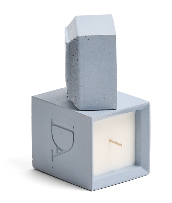 4oz Devetu artisanal candle in Muse, encased in powder blue concrete square vessel with a lid. The lid, featuring the embossed 'DA' Devetu Aroma logo, adds a sleek finish to the candle's modern aesthetic.