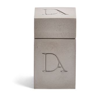 4oz Devetu artisanal candle in Odyssey, encased in ash grey concrete square vessel with a lid. The lid, featuring the embossed 'DA' Devetu Aroma logo, adds a sleek finish to the candle's modern aesthetic.