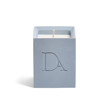 4oz Devetu artisanal candle in Muse, crafted in a powder blue concrete square vessel. The candle is uncovered, displaying the richly textured wax surface, with the 'DA' Devetu Aroma logo embossed on the front.