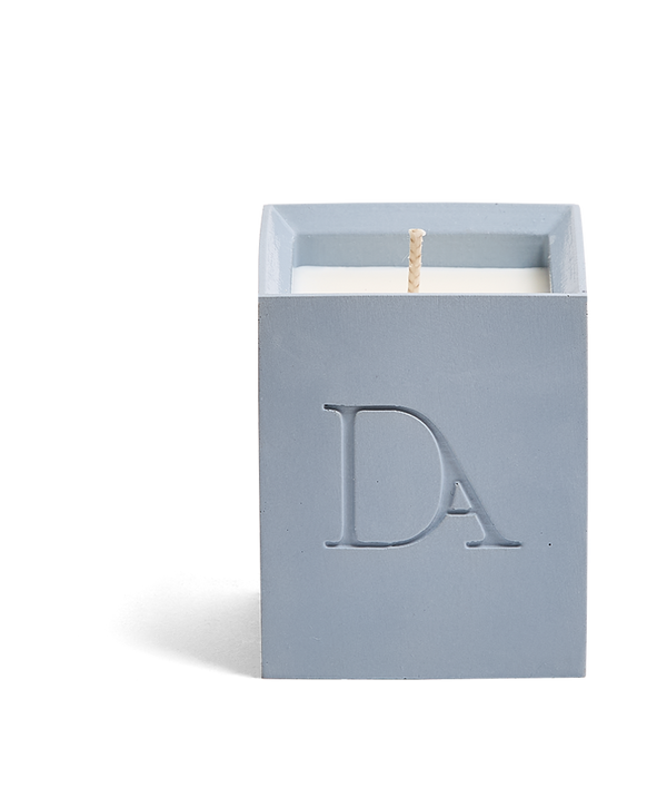 4oz Devetu artisanal candle in Muse, crafted in a powder blue concrete square vessel. The candle is uncovered, displaying the richly textured wax surface, with the 'DA' Devetu Aroma logo embossed on the front.