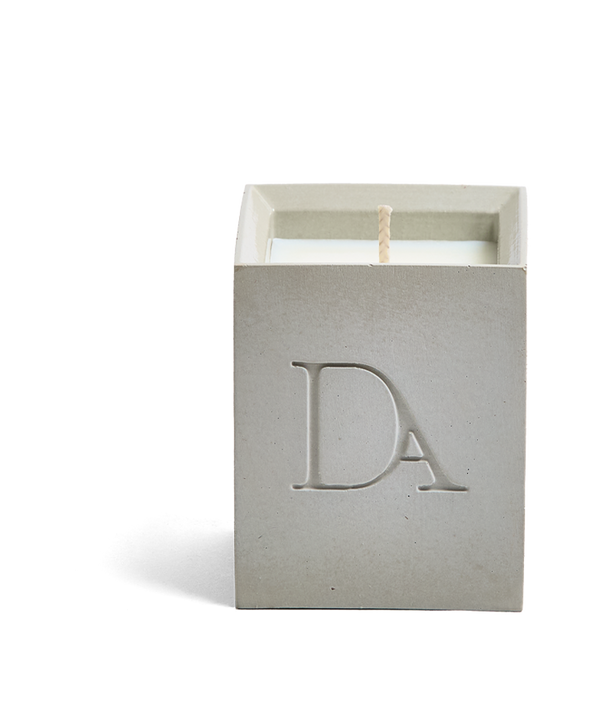 4oz Devetu artisanal concrete square candle named Skin, uncovered, showcasing the richly textured wax surface, in a natural concrete gray with ‘DA’ Devetu Aroma logo embossed on the front