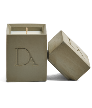 4oz Devetu artisanal candle in Wild Nomad, encased in deep olive green concrete square vessel with a lid. The lid, featuring the embossed 'DA' Devetu Aroma logo, adds a sleek finish to the candle's modern aesthetic.