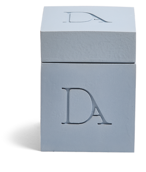 9oz Devetu artisanal candle in Muse, encased in powder blueconcrete square vessel with a lid. The lid, featuring the embossed 'DA' Devetu Aroma logo, adds a sleek finish to the candle's modern aesthetic.